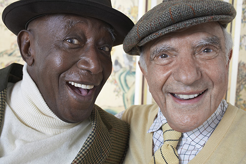 Close up of two men smiling both wearing hats